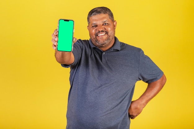 Brasilianischer schwarzer Erwachsener, der auf den negativen Raum des Handy-Bildschirms für Werbung zeigt