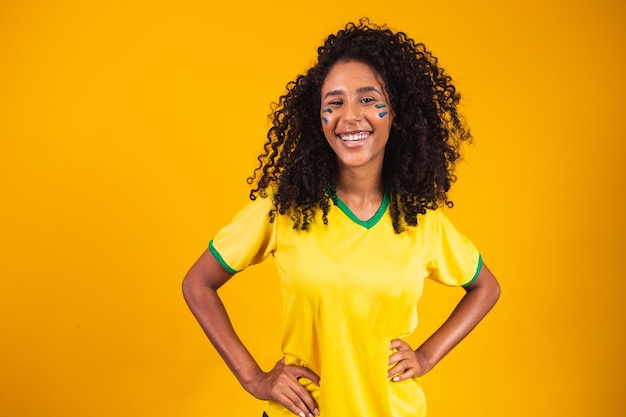 Brasilianischer Unterstützer. Brasilianischer Frauenfan, der auf Fußball- oder Fußballspiel auf gelbem Hintergrund feiert. Brasilien farben.