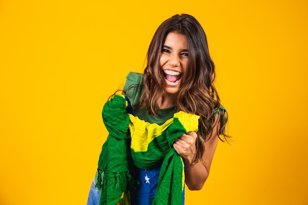 Brasilianischer Unterstützer. Brasilianischer Frauenfan, der auf Fußball- oder Fußballspiel auf gelbem Hintergrund feiert. Brasilien farben.