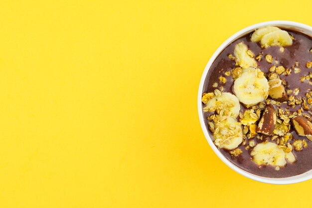 Brasilianisches Açai in einer weißen Schüssel mit Banane, Müsli und Kastanien.