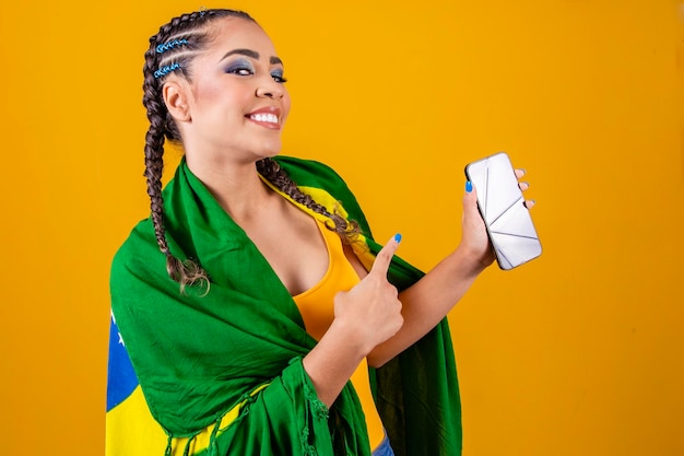 Foto brasilianisches fanporträt brasilianischer fan zeigt ihr handy, das als fußballfan oder fußballspiel auf gelbem hintergrund verkleidet ist brasilien färbt die weltmeisterschaft