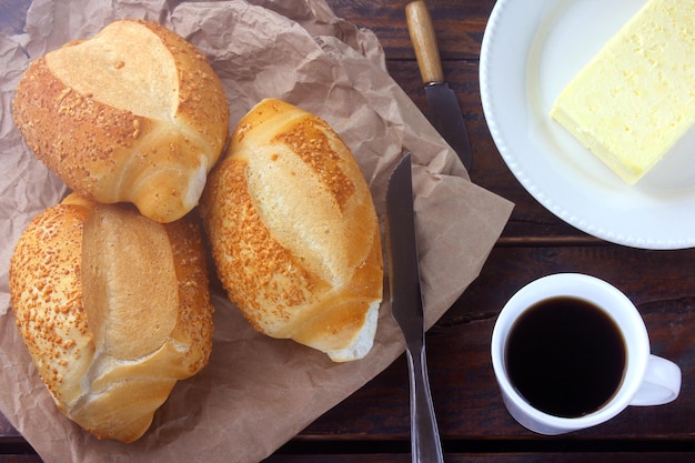 Brasilianisches französisches Brot, auf rustikalem Papier, auf rustikalem Holztisch zum Frühstück. Küche und Brasilien