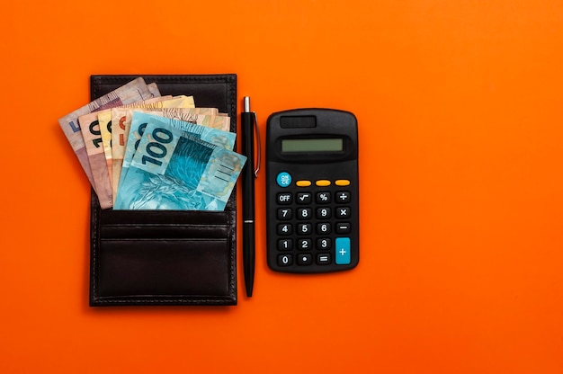 Brasilianisches Geld in Brieftasche, mit Notizblock, Stift und Taschenrechner.