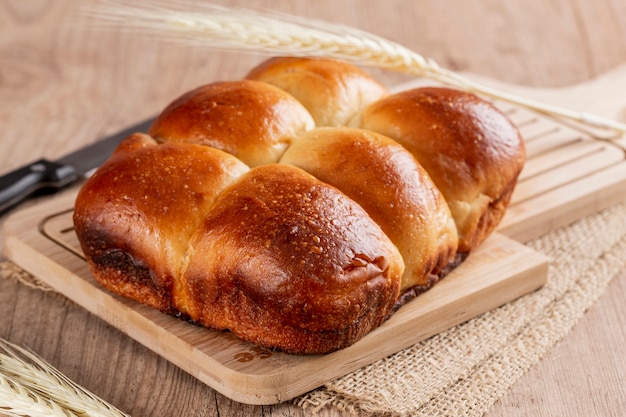 Brasilianisches hausgemachtes Brot auf einer hölzernen Arbeitsplatte, mit Mehl über der Theke und Weizen verteilt.