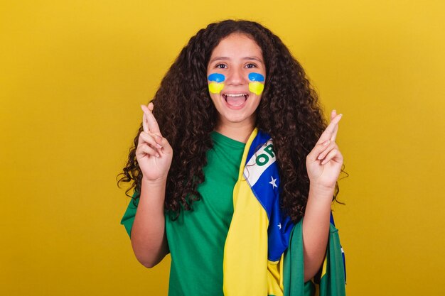 Brasilianisches kaukasisches Fußballfan-Mädchen Daumen drücken und hoffnungsvoll jubeln