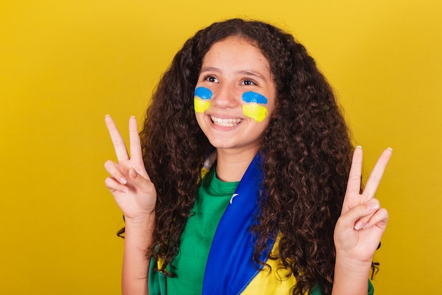 Brasilianisches kaukasisches Mädchen Fußballfan Nahaufnahme Foto Ausdruck von Frieden und Liebe Finger erhoben glücklich Pose für Foto World Cup Olympics