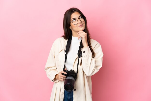 Brasilianisches Mädchen des jungen Fotografen lokalisiert auf rosa und nach oben schauend