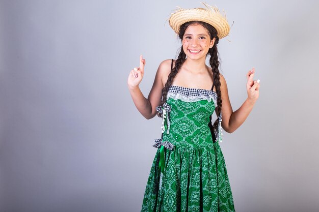 Foto brasilianisches mädchen mit kleidung von festa junina arraial festa de sao joao horizontales porträt drückt die daumen und hofft