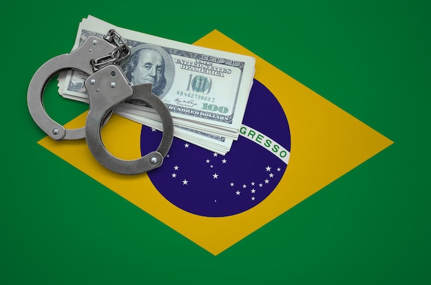 Brasilien-Flagge mit Handschellen und einem Bündel Dollar. Das Konzept, das Gesetz zu brechen und Verbrechen zu bestehlen