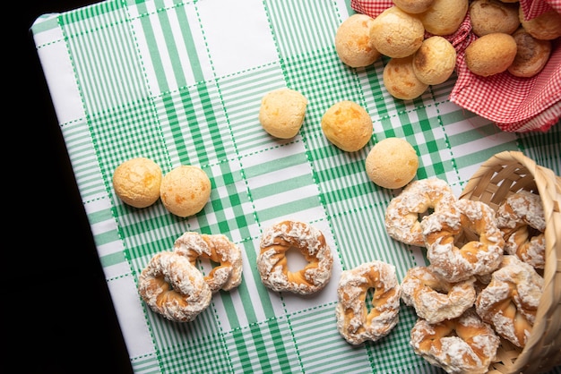 Brasilien-Käsebrot und süßer Keks auf einem Tisch mit grün karierter Tischdecke, Draufsicht.