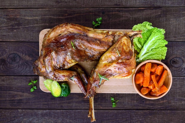 Braten Sie ein ganzes Kaninchen auf einem Holzbrett mit gebackenen Karotten und Rosenkohl