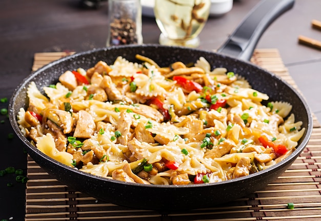 Braten Sie Hühnchen, Pasta Farfalle, Zucchini, Paprika und Frühlingszwiebeln an