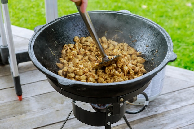 Braten von Schweinefleisch im Kessel im Freien auf Feuer für Pilaw.