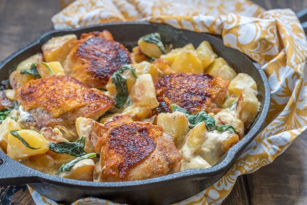 Brathähnchen, Kartoffeln und Spinat mit cremiger Sauce in einer Pfanne