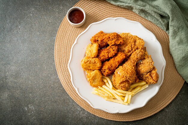 Brathähnchen mit Pommes Frites und Nuggets auf dem Teller - ungesundes Essen