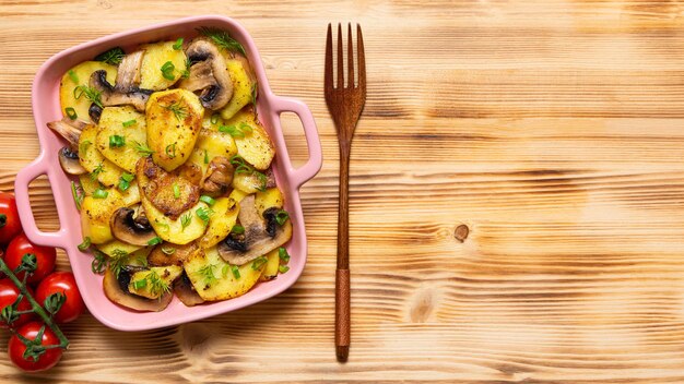 Bratkartoffeln mit verschiedenen Gewürzen und Kräutern auf einem Holztisch mit Tomaten und grünem Salat