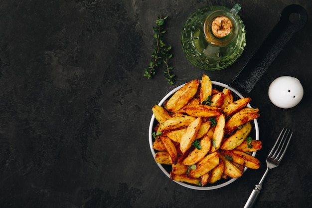 Bratkartoffeln Ofenkartoffelkeile in der Pfanne auf dunklem Steinhintergrund