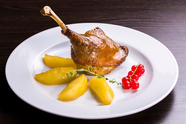 Bratkartoffeln und Ente mit Preiselbeersauce Bratkartoffeln auf einem Teller mit Entenbein