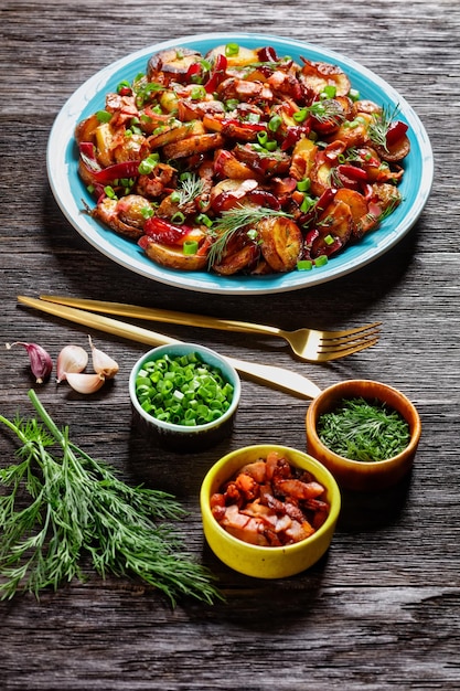 Bratkartoffelsalat Bratkartoffelsalat mit roten Zwiebeln und Speck auf einem blauen Teller auf einem dunklen rustikalen Holztisch vertikale Ansicht deutsche Küche