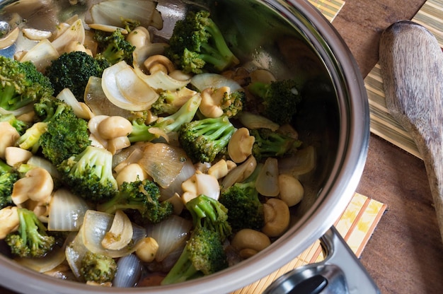 Bratpfanne mit Brokkoli, sautierten Champignons, geschnittenem Knoblauch und grob gehackten Zwiebeln in der Bratpfanne