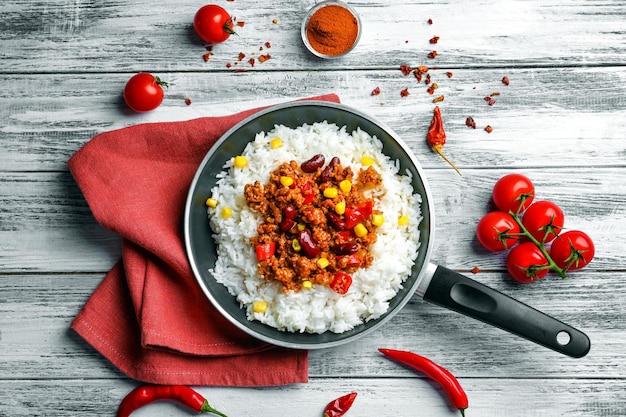 Bratpfanne mit Chili con carne und Reis auf hölzern Hintergrund