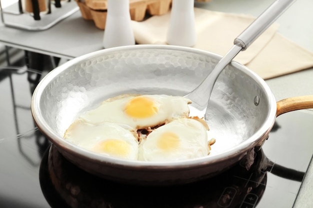 Bratpfanne mit Eiern und Spachtel auf dem Herd