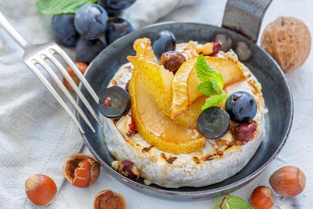 Bratpfanne mit gebackenem Camembert, karamellisierten Birnen und Weintrauben