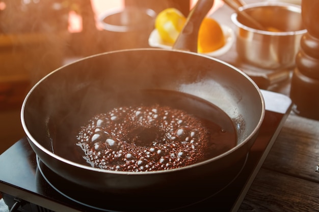 Bratpfanne mit kochender Flüssigkeit dunkle Flüssigkeit mit Blasen süßes Aroma von Rotweinkocher im Bistro...