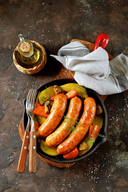 Bratwürste mit Kartoffeln, Pilzen und Zwiebeln in einer Pfanne