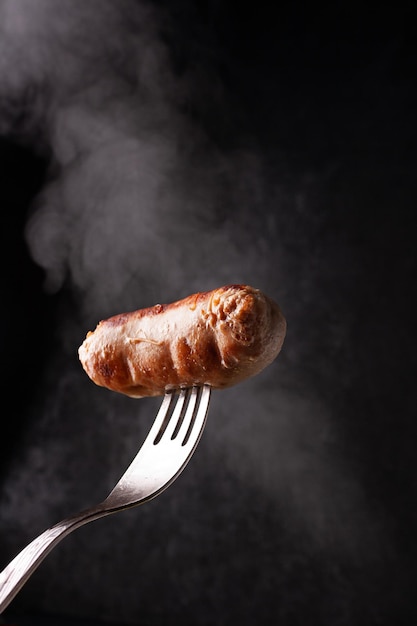 Bratwurst auf einer Gabel in Rauchwolken selektiver Fokus