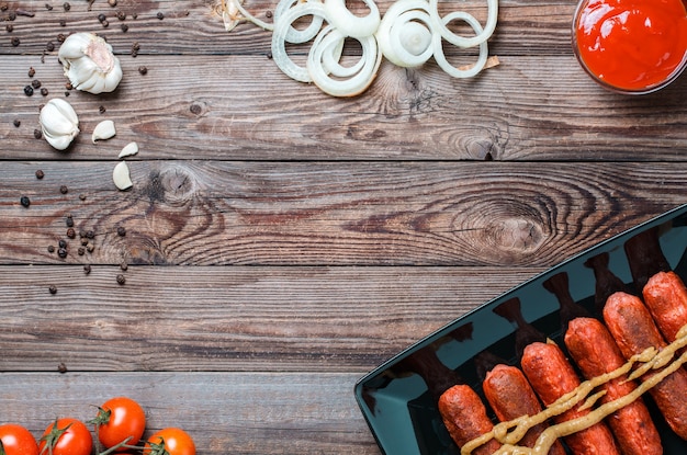 Bratwurst in schwarzer Platte auf Holztisch. Draufsicht mit leerem Platz für Text, Logo usw.