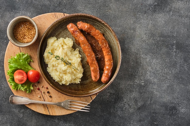 Bratwurst de ternera a la parrilla con puré de patatas en un plato moderno sobre una tabla de madera Salchichas de ternera a la barbacoa