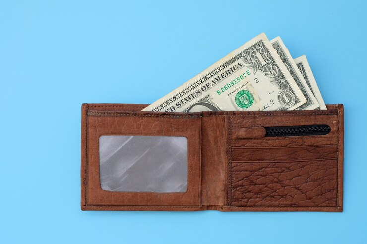 Braune Brieftasche aus Leder mit Dollar-Banknoten auf blauem Grund