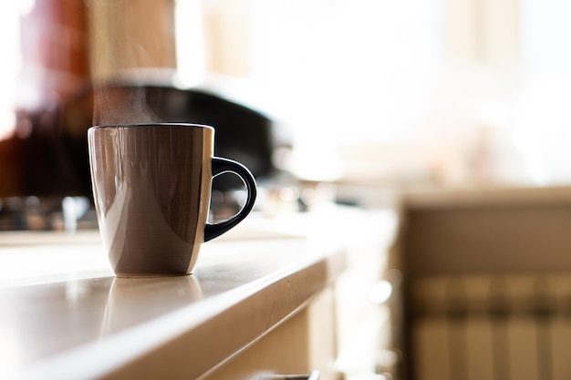 Braune Kaffeetasse auf Küchentisch mit echtem Tageslicht und Dampf