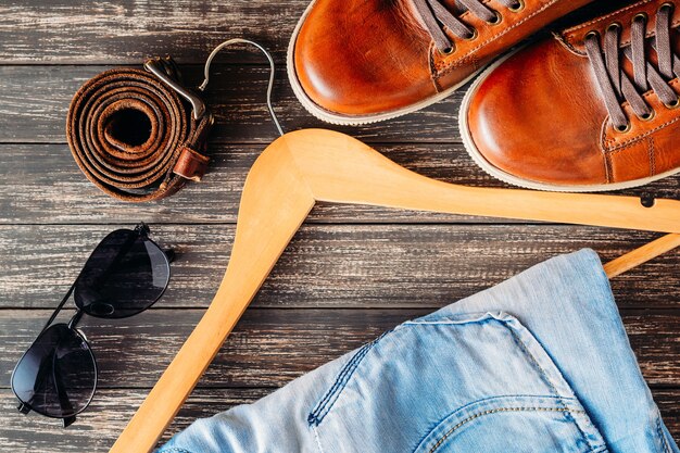 Braune Leder Freizeitschuhe Jeans auf Kleiderbügel, Gürtel und Sonnenbrille