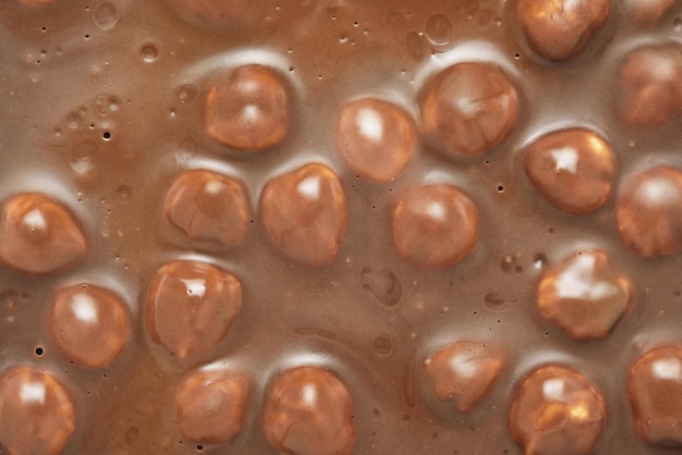 Braune Milchschokolade mit ganzen Haselnüssen im Hintergrund