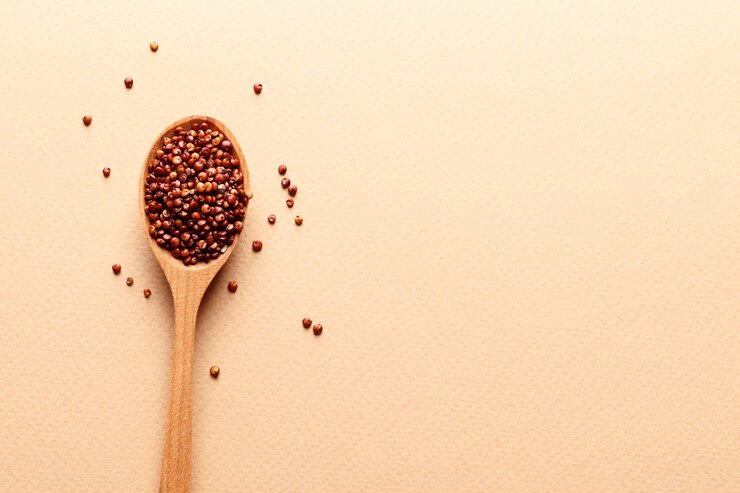 Braune Quinoa in einem Holzlöffel auf beigem Hintergrund