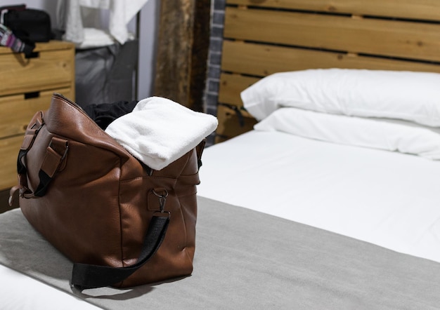 Braune Reisetasche auf dem Bett im Hotelzimmer