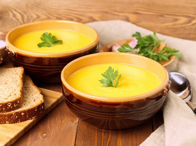 Braune Schüssel zwei Kürbissuppe mit Petersilie auf braunem dunklem hölzernem Hintergrund, Seitenansicht