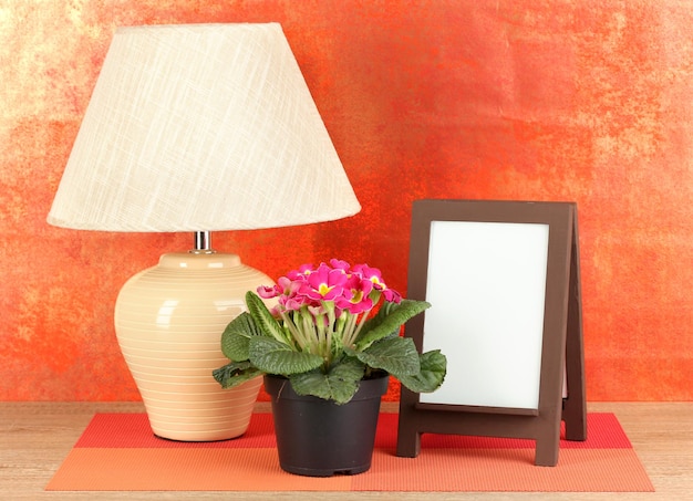 Brauner Fotorahmen und Lampe auf Holztisch auf rotem Wandhintergrund