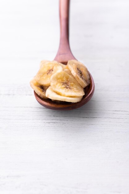 Foto brauner holzlöffel mit bananenscheiben auf weißem hintergrund für katalog