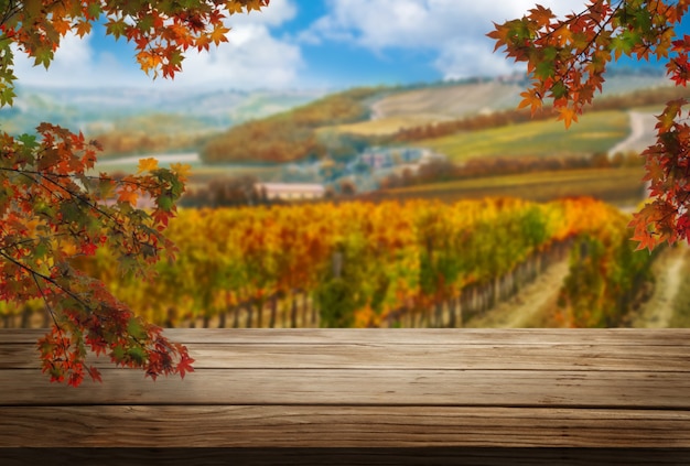 Brauner Holztisch in der Weinberglandschaft im Herbst mit leerem Raum für Produktanzeigemodell.