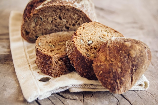 Braunes frisches Brot mit Samen wird auf altem Holzhintergrund in Stücke geschnitten. Ansicht von oben, Textfreiraum