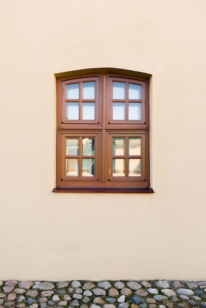 Braunes Holzfenster in einem beigen Haus