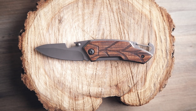 Braunes Messer und Scheibe eines Baumes auf Holztisch.