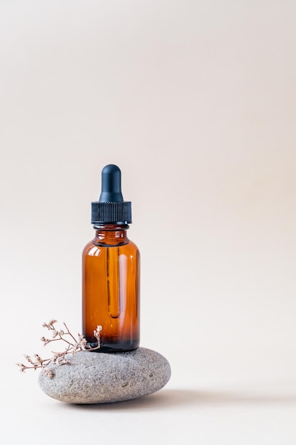Braunglas-Tropfflasche mit schwarzem Deckel auf einem Podium auf Steinen Hautpflegeprodukte Naturkosmetik Schönheitskonzept für Gesichts- und Körperpflege