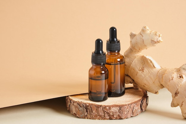 Braunglas-Tropfflaschen und Ingwerwurzel auf beigem Hintergrund kopieren Raum Naturkosmetikkonzept, Flaschen mit Öl oder Serum auf Holzständer, Aromatherapie