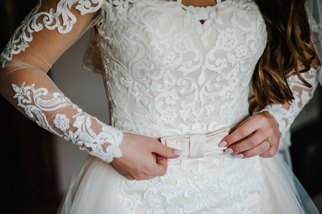 Braut befestigen Gürtel Nahaufnahme im Hochzeitskleid und bekommen ihr Kleid