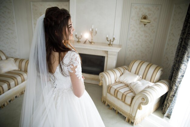 Braut der jungen Frau, die Hochzeitskleid bei moderner Hochzeit anprobiert, glücklich und lächelnd