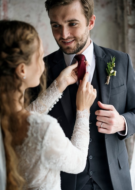 Braut, die dem Bräutigam Dressing Up für Hochzeitszeremonie hilft